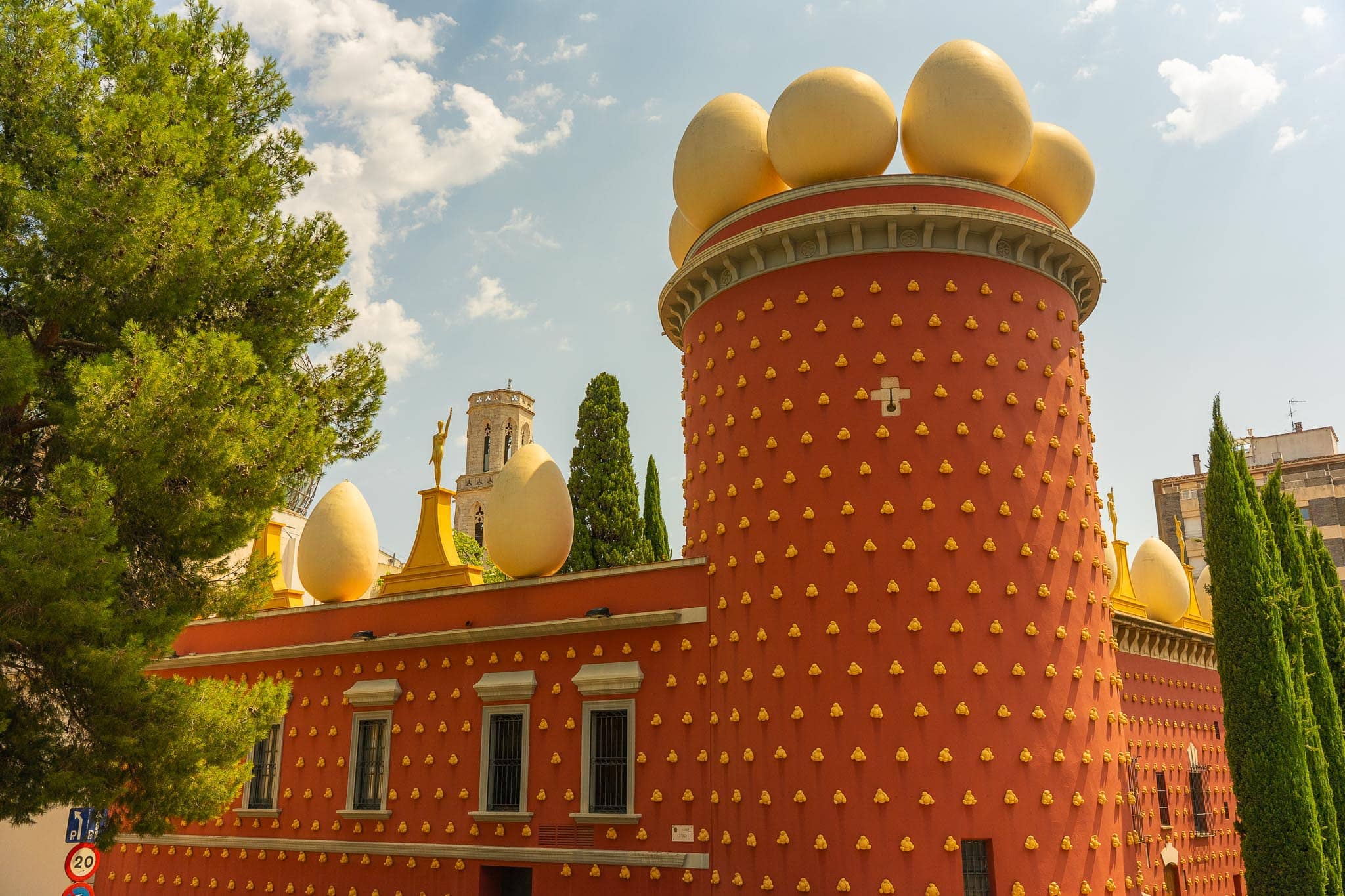 The Teatre-Museu Dali at Figueres: a deep red building studded with gold bread-roll shapes, topped by a row of giant white eggs against the sky.