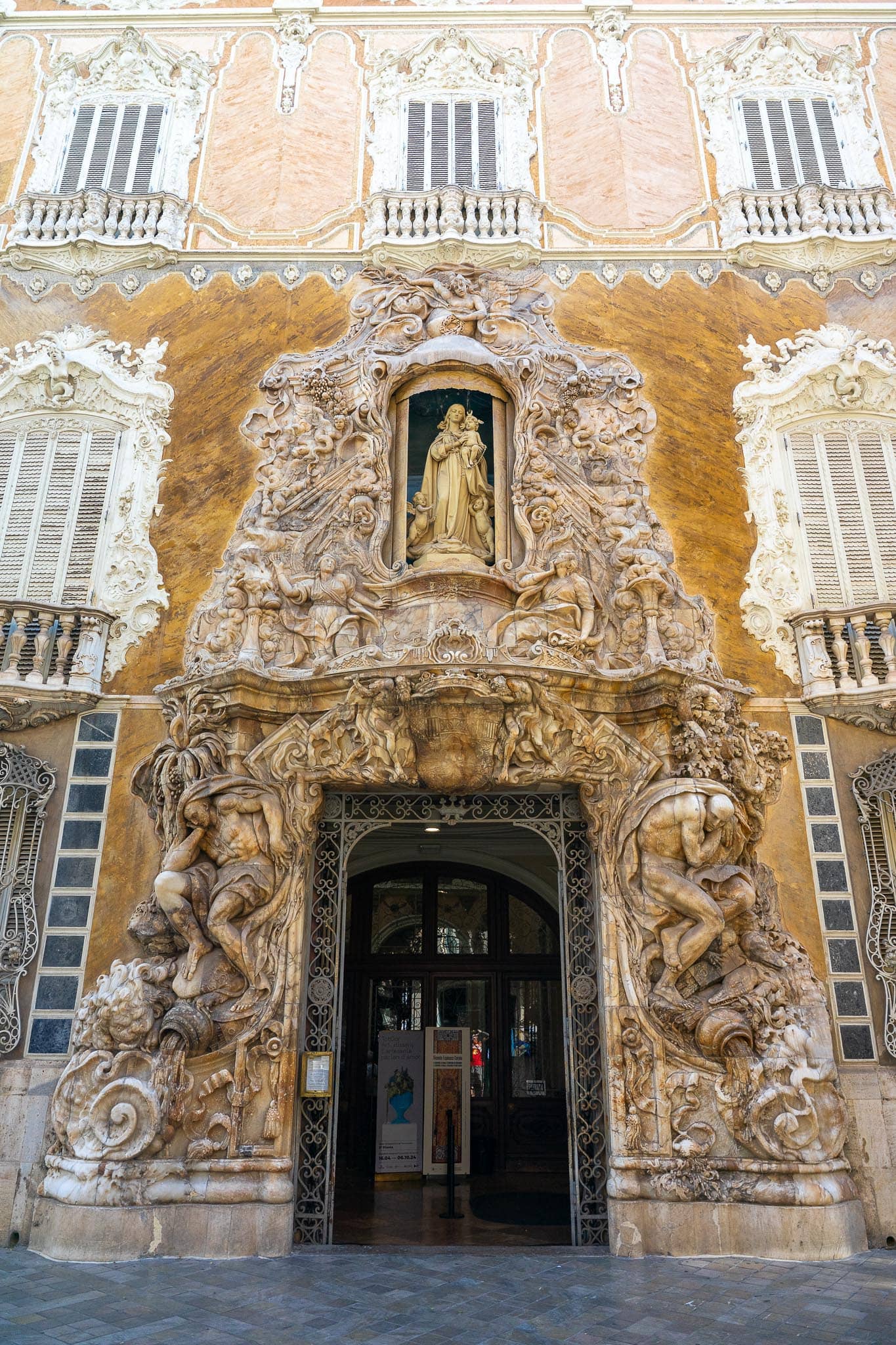 The carved alabaster portal of the Palacio del Marques de Dos Aguas in Valencia, with two reclining figures flanking the doorway and a statue in a niche above.