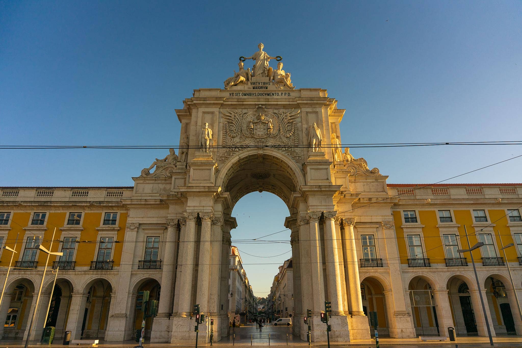 The triumphal Arco da Rua Augusta on the Praca do Comercio in Lisbon, flanked by the yellow arcaded buildings of the rebuilt lower town.
