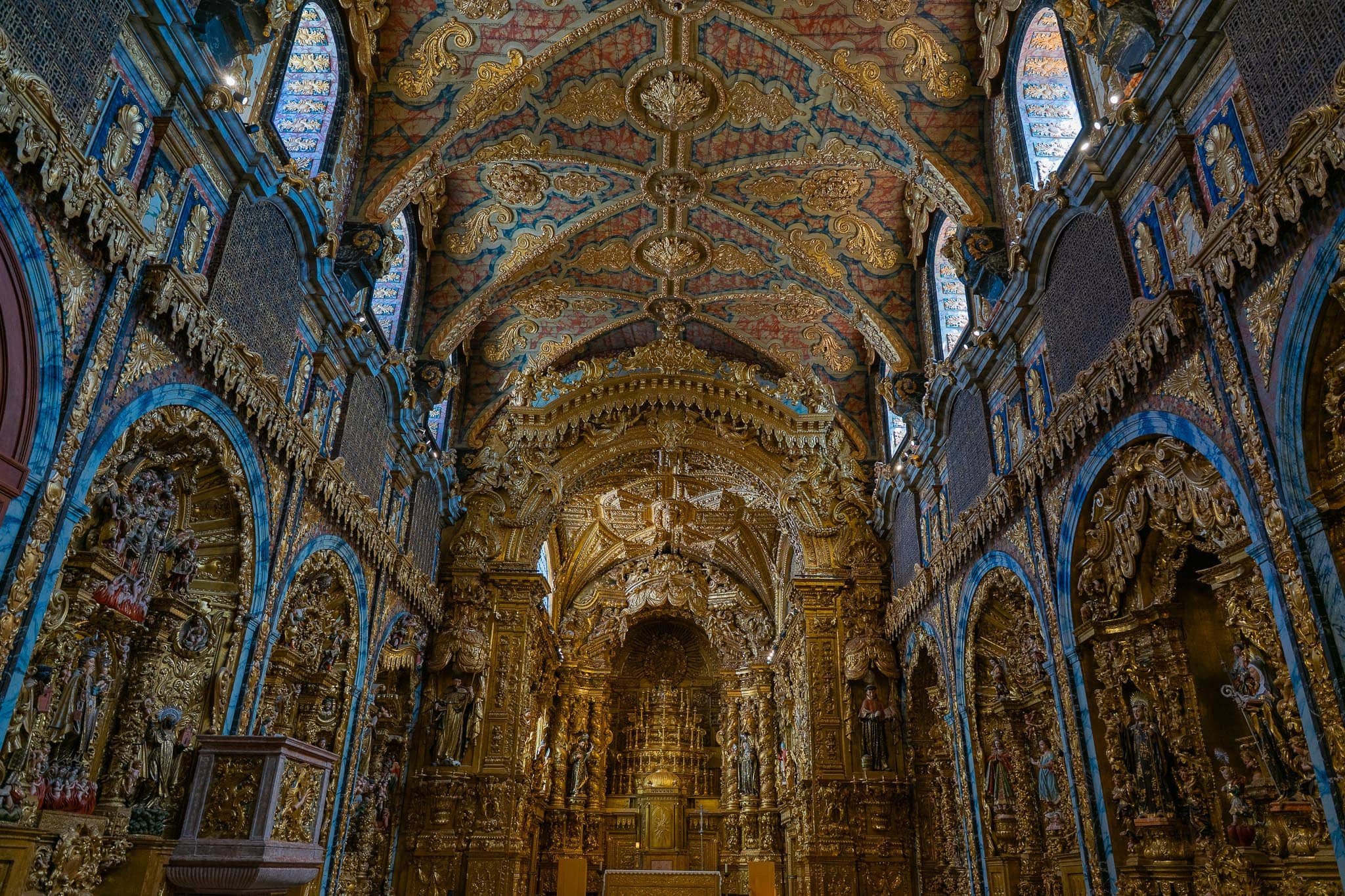 A church interior in Porto whose nave, arches and barrel vault are entirely covered in carved gilded woodwork picked out in blue and gold.