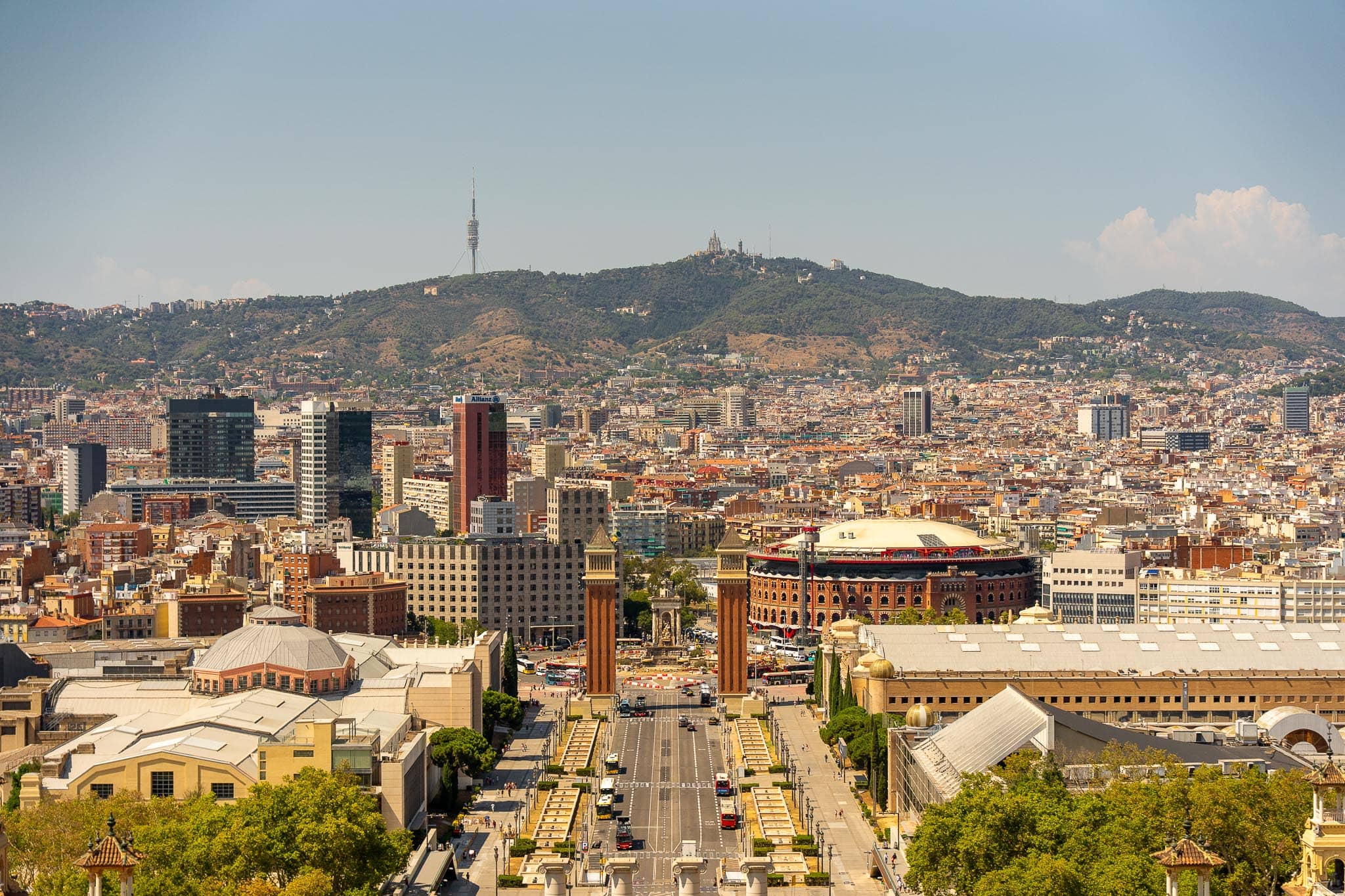 Barcelona seen from Montjuic: the twin towers of Placa d'Espanya and the avenue running north into the city grid, with the Collserola ridge behind.