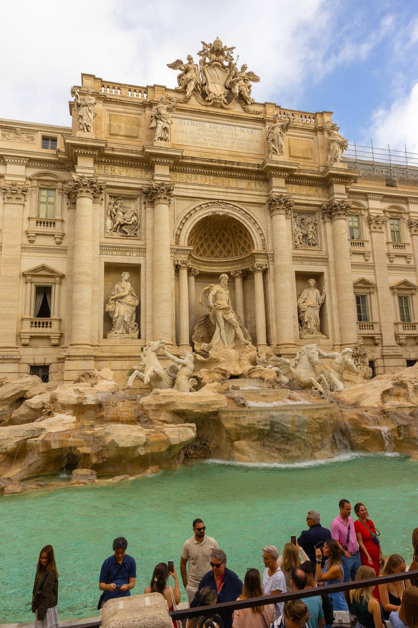 The Trevi Fountain in Rome: Oceanus in his shell chariot among the travertine rockwork, turquoise water in the basin, and a dense crowd at the railing in front.